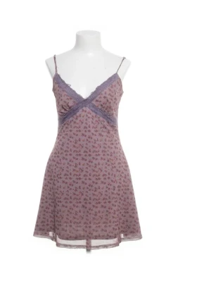 Lila blommig miniklänning med spets - Söt klänning i lila mesh med små blommor och tunna axelband. V-ringad hals med spetsdetaljer och lätt utsvängd passform.