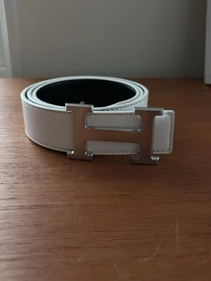 H bälte - Snyggt bälte med H logga vitt med silvrig logga 110 cm 