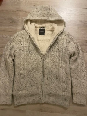 Fodrad sticksd cardigan - Otroligt snygg vit/grå fodrad stickad cardigan med fint mönster. Passar perfekt till kallare väder. Priset kan såklart diskuteras!