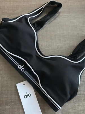  Sport-bh Alo - Snygg svart sport-bh från Alo. Bh:n har breda band och är i ett stretchigt och mjukt material som passar perfekt till träning 🖤storlek L, passar M