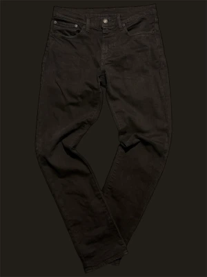  Levi's 511  - Snygga svarta Levi's 511 jeans med klassisk femficksdesign och smal passform. Jeansen har normal midja och raka ben, tillverkade i mjukt bomullsmaterial med stretch för extra komfort. Perfekta till en avslappnad streetwear-look.