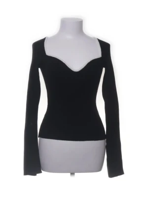 Svart långärmad topp med v-ringning - Snygg svart långärmad topp med djup v-ringning och figurnära passform. Toppen har en unik skärning vid halsen som ger en modern och trendig look. Perfekt att styla med jeans eller kjol för en cool outfit.