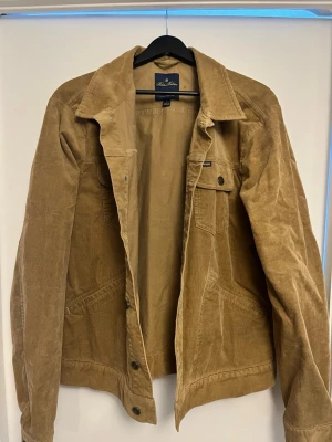  manchesterjacka Brooks Brothers - beige jeansjacka från Brooks Brothers i mjuk manchester. Klassisk modell med krage, knappstängning och bröstficka med knapp. Bara att höra av er om ni undrar något 