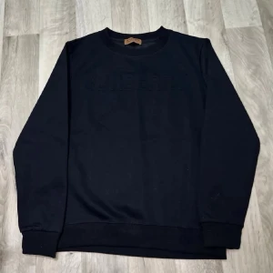 Svart sweatshirt från Burberry - Stilren svart sweatshirt från Burberry med diskret broderad logga framtill. Tröjan har rund halsringning, långa ärmar och ribbade muddar vid ärmslut och nederkant. Perfekt för en clean och klassisk look.