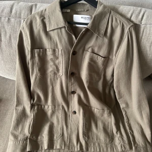 Beige overshirt från Selected Homme - Riktigt snygg beige overshirt från Selected Homme med klassisk krage och fyra stora fickor framtill.  Strl S, skick 10/10.            Säljer för 379kr