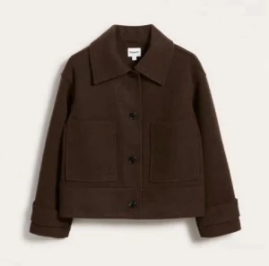 Brun jacka från Kappahl - Kort jacka i skepparstil samt rak och vid modell med krage, dubbelknäppning framtill och fickor på framsidan. Jackan har även ett band vid ärmslut med en knapp som en snygg detalj. Jackan är i fint skick, inga defekter.