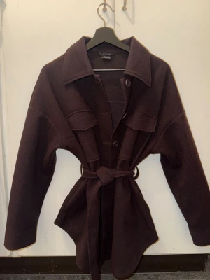 Brun kort kappa - Snygg mörkbrun overshirt från Gina Tricot med knappar framtill, stora bröstfickor och ett matchande bälte i midjan. Jackan har en loose passform som ger en chill vibe. Perfekt och mysig höstjacka😍.