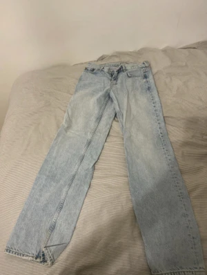 Ljusblå raka jeans - Säljer ett par ljusblå jeans med klassisk rak passform och fem fickor. Jeansen har en enkel design utan synliga detaljer och är tillverkade i jeansmaterial. Perfekta för dig som gillar en clean och avslappnad stil. Dem är lågmidjade och passar till allt 