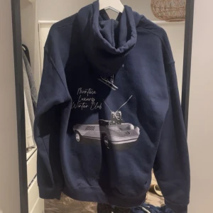 Montéva limited edition hoodie - Säljer en mörkblå hoodie från Monteiva med coolt tryck på ryggen som visar en bil och skidåkare samt texten 'Montéva Luxury Winter Club'. Hoodien har huva med snörning och en stor magficka framtill. Perfekt för dig som gillar streetwear och vintervibes. Nästintill nytt skick. Skriv om du undrar något🤩