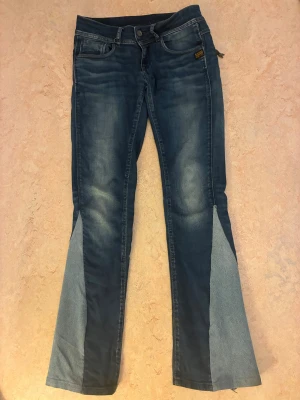 Blå bootcut jeans från G-Star RAW - Snygga blå jeans från G-Star RAW med bootcut passform och coola ljusare denim-paneler nedtill. Klassisk femficksdesign, detaljerade sömmar och dragkedjor på bakfickorna. Märkespatch framtill och bak. Perfekt för dig som gillar unik stil.