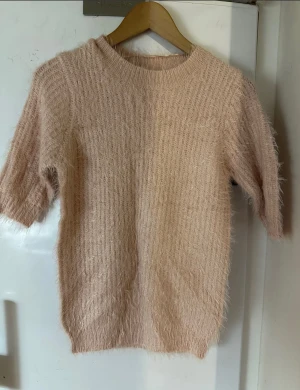 Ny tröja från Gina Tricot st. S - Supermjuk och fluffig stickad tröja i ljusrosa ton. Tröjan har en rund halsringning och halv-långa ärmar, perfekt för dig som gillar en cozy och chill vibe. Tröjan har en mjuk, fluffig textur.  60% polyamid, 40% akryl  Modell: Florence knitted sweater   Obs! Saknar prislapp/ etikett men klistermärken är kvar på bild 2= ny