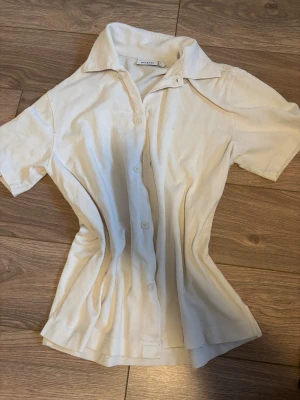 Vit kortärmad skjorta från Weekday - Fräsch vit skjorta från Weekday i storlek XS. Skjortan har klassisk krage, korta ärmar och knäppning framtill med vita knappar. Materialet är mjuk bomull med lätt struktur, små fläckar på framsidan men syns knappt 