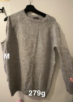 Grå stickad tröja i medium - En enkel och stilren grå stickad tröja i storlek M. Tröjan har rund hals, långa ärmar och ribbade muddar vid ärmslut och nederkant. Perfekt för att hålla sig varm under kyliga dagar och passar till de flesta outfits.🌸 Fint använt skick. Öppningar vid axlarna ( som denna typ av tröja har, alltså ingen defekt )