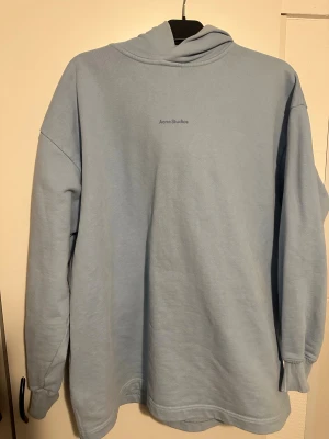 Ljusblå hoodie från Acne Studios - Säljer en ljusblå hoodie från Acne Studios i storlek S. Tröjan har en klassisk huva, ribbade muddar och är tillverkad i mjuk 100% bomull. Minimalistisk design med Acne Studios-logga på bröstet. Perfekt för chill dagar och enkel att matcha med jeans eller joggers. Pris kan diskuteras 