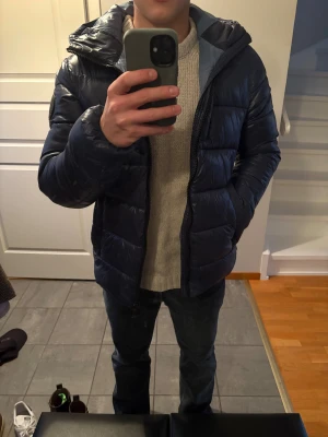 Mörkblå pufferjacka Save The Duck - Skön mörkblå pufferjacka från Save The Duck med huva och dragkedja. Jackan är i bra skick och perfekt för kalla dagar!