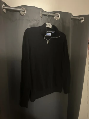 Svart half zip tröja Jack & Jones - Svart långärmad tröja från Jack & Jones med half zip-dragkedja i halsen. Tröjan har en enkel och clean look med ribbade muddar och normal passform. Perfekt att slänga på sig när det är lite kyligt ute. Det finns defekt❗️