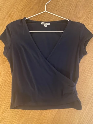 Mörkblå omlottopp från Subdued - Snygg mörkblå omlottopp från Subdued i mjuk bomull. Toppen har korta ärmar och en djup v-ringning.