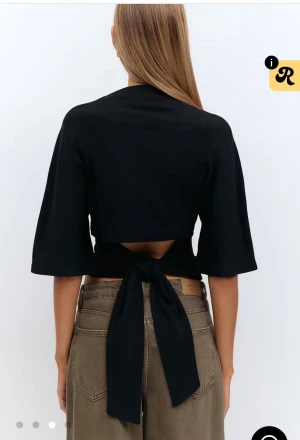 Svart topp med knyt i ryggen - Toppen har en öppen rygg med stort knytband som ger en cool detalj.