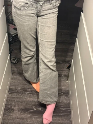 Grå bootcut jeans från Gina Tricot - Snygga grå jeans från Gina Tricot i storlek 152. Modellen har bootcut-ben och klassisk femficksdesign med knapp och dragkedja framtill. Jeansen är tillverkade i mjukt denimtyg och har en cool, ljusgrå tvätt som passar till allt.