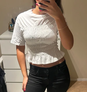 Vit topp/t-shirt från Gina Tricot - Säljer en vit topp med lite längre ärmar och struktur så att passformen blir lite figurativ. Toppen är från Gina Tricot i storlek XS! ALDRIG använd!! 