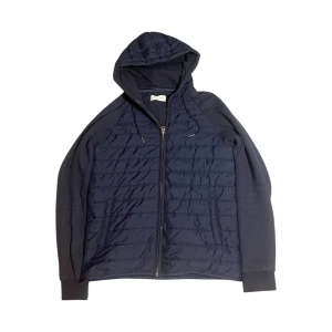 Mörkblå quiltad cardigan Pier One - Quiltad mörkblå cardigan från Pier One med huva och dragkedja framtill. Jackan har ribbade muddar vid ärmslut och snygga paneler i olika material. Perfekt för dig som gillar stilren och sportig look.