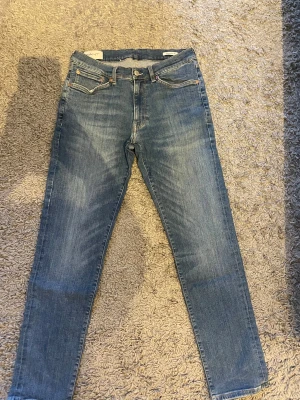 Blå extra-slim jeans från Gant - Snygga blå jeans från Gant med extra-slim fit. Klassisk femficksmodell, raka ben och medelblå tvätt. Jeansen har knapp och dragkedja i gylfen samt läderpatch bak i midjan. Perfekt för dig som gillar en smal siluett och stilren look.