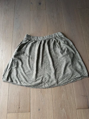 Kjol från Pieces - Kjol från Pieces i grön färg med beige leopardmönster Kjolen har resår i midjan och två fickor. Kjolen är i viskos.   Obs: Alla plagg säljs endast fram till 28/12