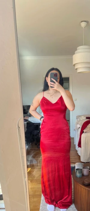 Röd långklänning med tunna axelband - Röd långklänning från NA-KD med tunna axelband och v-ringning. Klänningen har en figurnära passform och öppen rygg. Materialet är glansigt 