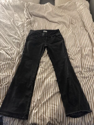 Svarta bootcut jeans  - Svarta jeans från Gina Tricot i bootcut med medelhög midja. Jeansen har två knappar och dragkedja fram, klassiska fem fickor samt bakfickor med lock och knapp. Storlek 40