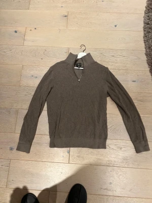 Brun stickad half zip tröja H&M - Slim fit stickad tröja från H&M i brun färg med ribbad struktur. Tröjan har en hög krage och half zip-dragkedja framtill. Långärmad modell som passar perfekt för lager-på-lager under höst och vinter. Enkel och stilren design som funkar till jeans eller chinos. Org pris ca 400