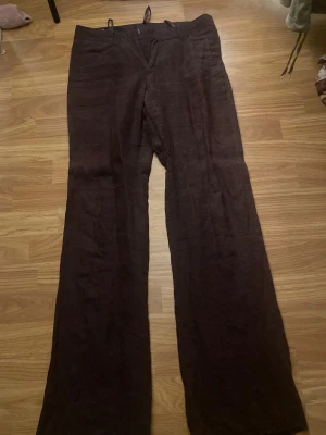 Bruna linnebyxor med wide fit - Snygga bruna linnebyxor med breda ben och klassisk passform. Byxorna har bälteshällor, sidfickor och bakfickor med knapp. Perfekta för dig som gillar en chill och luftig stil. Materialet är linne och färgen är mörkbrun.