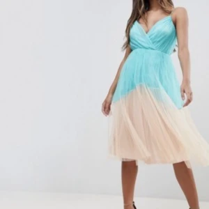 Turkos och champagneklänning från ASOS - Säljer en drömmig långklänning från ASOS i turkos och champagnefärgad mesh. Klänningen har omlottliv med v-ringning och är ärmlös. Kjolen är i flera lager tunn tyll som ger ett svävande intryck. Perfekt för dig som vill sticka ut med en färgstark look.