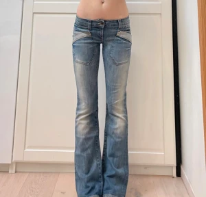 bootcut jeans - Säljer ett par snygga only jeans med bootcut och låg midja. De är ljusblå med slitningar och har coola fickdetaljer fram och bak, samt röda sömmar på bakfickorna.                                      Gren: 17,5 cm                                                     Midjemått: 38 cm                                                inneben: 81cm                                                              lår: 21 cm 