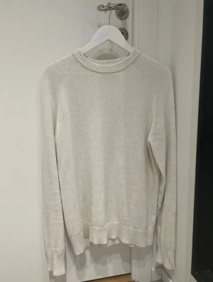 Vit stickad tröja från Bläck, M - Snygg vit stickad tröja från Bläck i storlek M. Modellen heter Barclay Crewneck och har en rundad, ribbad hals samt ribbade muddar vid ärmslut och nederkant. Perfekt för dig som gillar enkel och clean stil med mjukt material.
