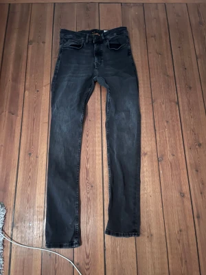 Svarta slim fit jeans från BOSS 30/32 - Snygga svarta jeans från BOSS i modellen Delaware Slim Fit. Jeansen har klassisk femficksdesign, diskret tvättad look och är tillverkade i stretchigt denim för extra komfort. Perfekta för dig som gillar en smalare passform och stilren vibe.