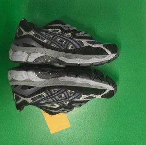 Svarta och grå Asics sneakers strl 36 - Snygga Asics sneakers i svart och grått med coola meshpaneler och detaljer i syntet. Skorna har snörning och en platt sula som ger skön komfort. Perfekt för dig som gillar sportig stil och vill ha ett par riktigt fräscha sneakers.
