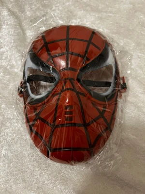 Spiderman masker röd och svart - Två coola Spiderman-masker i plast, en i rött med svarta spindelnätslinjer och en i svart med vita linjer. Maskerna har öppningar för ögonen och elastiskt band för att sitta bekvämt på huvudet. Perfekt för cosplay eller maskerad! 65kr/st 