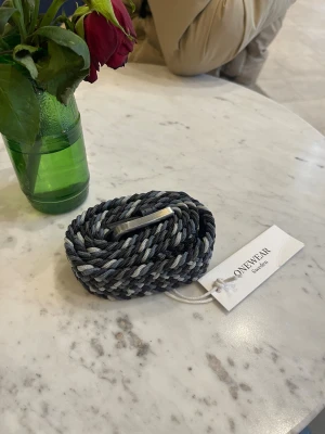 One wear Flätat bälte - Ett flätat bälte från one wear, storlek 80, helt nytt inte använt någon gång. Blå, marinblå, grå och vit färg.  Har gått ned mycket i pris och kan därför inte gå under det nuvarande priset.