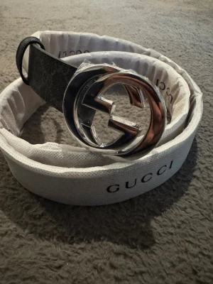 Svart G bälte  - Säljer ett stilrent svart bälte med spänne. Bältet är tillverkat i skinn och har en exklusiv vibe som lyfter vilken outfit som helst. Perfekt för dig som gillar designeraccessoarer.