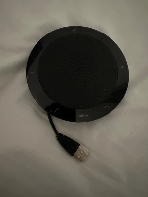 Jabra Speak 410 USB Speakerphone - Jabra Speak 410 är en kompakt USB kabel för konferenssamtal. Enkel plug-and-play via USB, tydliga touchknappar för volym och samtal. Produkten ser ut att vara i gott skick utan synligt slitage. Perfekt för möten och distansarbete och även lyssning på musik