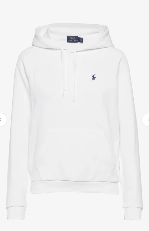 Vit hoodie från Polo Ralph Lauren - Vit hoodie från Polo Ralph Lauren med klassisk blå logga på bröstet. Tröjan har huva med snörning, stor magficka och ribbade muddar vid ärmslut och nederkant. Nypris ca 1300kr