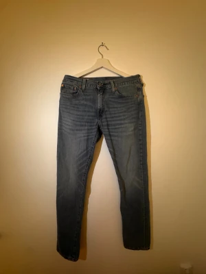 Levi's 502 ljusblå jeans W30 L34 - Ljusblå Levi's 502 jeans med klassisk femficksdesign och snyggt slitna detaljer. Jeansen har raka ben och slim fit, tillverkade i mjukt denimtyg. Perfekta för dig som gillar den trendiga stilen som är just nu. 