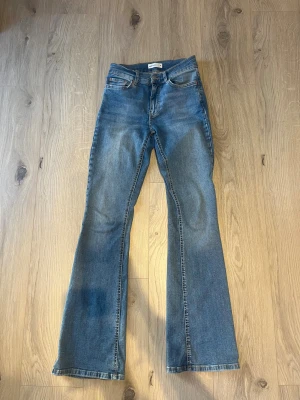 Blå bootcut jeans från Gina Tricot strl 34 - Snygga blå bootcut jeans från Gina Tricot, modell Perfect Jeans. Klassisk femficksdesign, normal passform och normal midja. Jeansen är tillverkade i mjukt denim med lätt tvättad look och har dragkedja och knapp framtill.