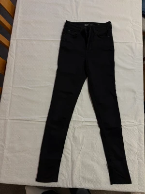 Svarta high waist jeans Hannah Cubus - Svarta high waist jeans från Cubus, modell Hannah. Skinny fit med klassiska fem fickor och extra fickdetalj på benet. Materialet är 90% bomull, 6% polyester och 4% elastan för stretchig och bekväm känsla. Snyggt svarta och passar perfekt till din vardagsstil.