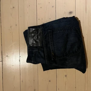 Mörkblå jeans från Lee straight fit - Snygga mörkblå jeans från Lee med klassisk straight fit och fem fickor. Jeansen har ett stilrent svart läderpatch med Lee-loggan bak i midjan och är gjorda i slitstarkt denim. Perfekta för dig som gillar enkel och tidlös stil.