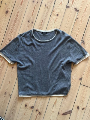 Dubbel tshirt - T shirt i grått med en vit kant, som att det är en till t shirt under! Väldigt skönt tyg i ull och silke. Ganska kort modell