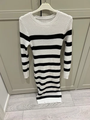 Randig stickad klänning i svart och vitt -  stickad klänning med svarta och vita breda ränder från shein. Modellen är långärmad och har en rund halsringning. Klänningen är ribbad och har en kroppsnära passform 