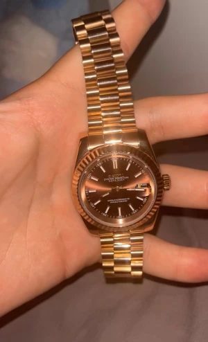 Seiko guld herrklocka - Säljer en snygg Seiko herrklocka i guld med klassisk länkarmband och mörk urtavla. Klockan har tydliga indexmarkeringar, datumfunktion och räfflad bezel. Perfekt för dig som gillar exklusiva accessoarer med lyxig känsla.