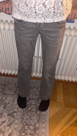 Low waist bootcut jeans  - Snygga grå jeans med klassisk femficksdesign och utsvängda ben. Jeansen har en normal midja och är tillverkade i mjukt denimtyg som ger en skön känsla. Perfekt för dig som gillar en enkel och stilren look. Passar till både sneakers och boots.