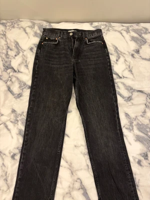Svarta straight jeans från Gina Tricot - Svarta jeans från Gina Tricot Perfect Jeans i rak modell med råa, fransiga benslut och klassisk femficksdesign. Jeansen har hög midja och dragkedja framtill. Säljer då jag ej använder dom.